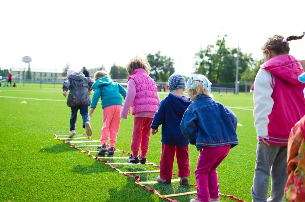 Children running and playing outdoors on a grass sports field
